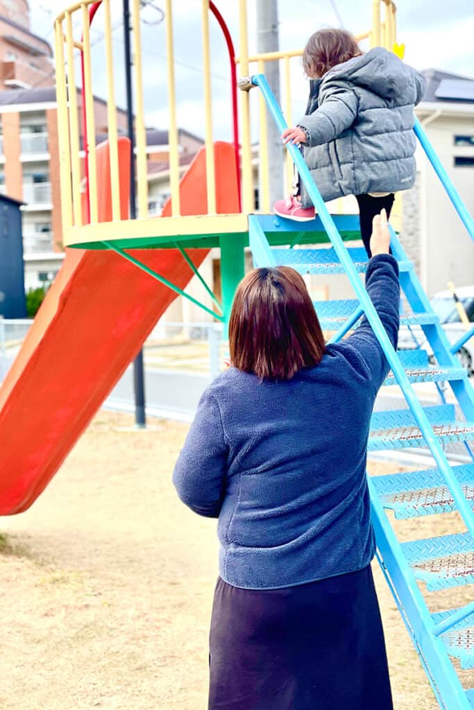 公園のすべり台で遊ぶ女性と孫